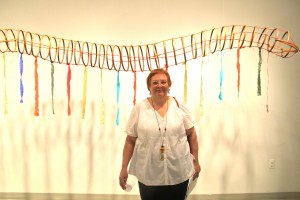 Artist Mary Fortuna in front of a large hanging snake piece; the snake and ourobouros being a strong motif throughout the gallery.