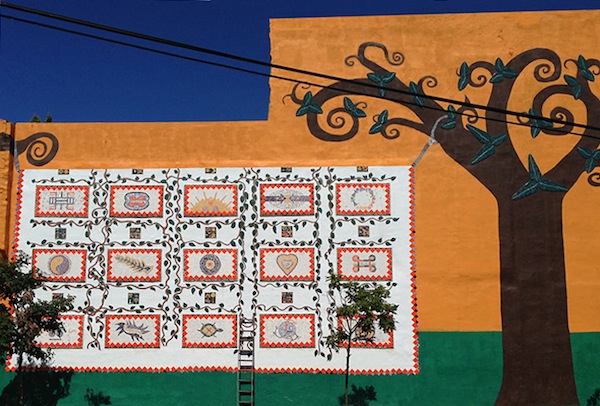 Unity Garden wall art features a quilt of unity symbols from around the world.