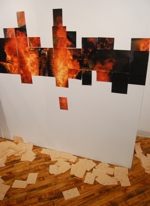 Pixels in the form of rectangular printouts form the image of a burning house.