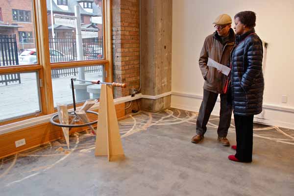 Members of the opening night crowd consider, "Drawing Machine." The machine&squot;s handiwork is evident on the floor.