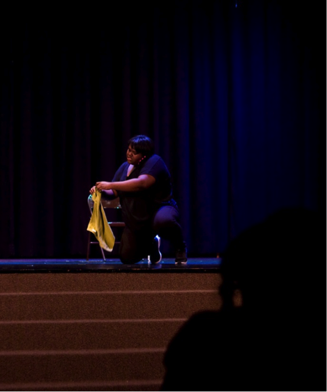 Actress Ainyé AnnaDora performs a monologue while a student audience member looks on.