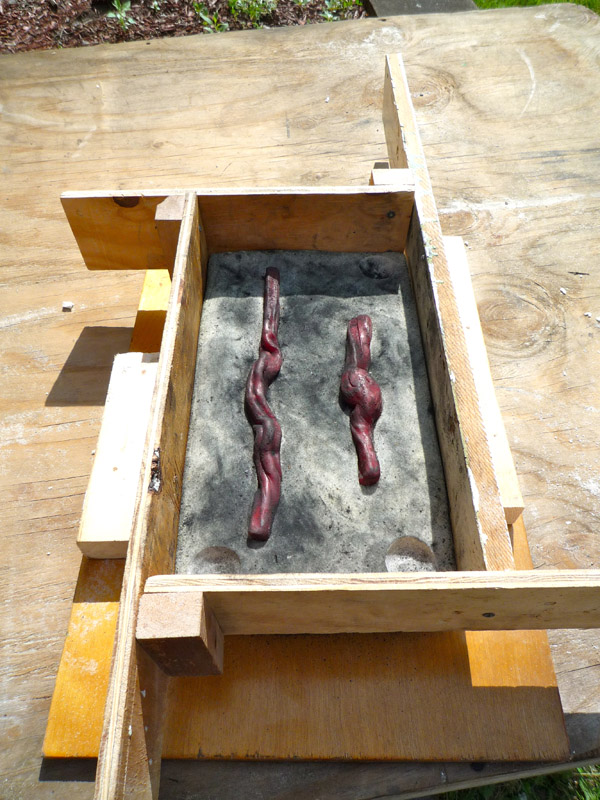 Once one half of a mold is complete, it is framed and dusted with charcoal to pour the other side.