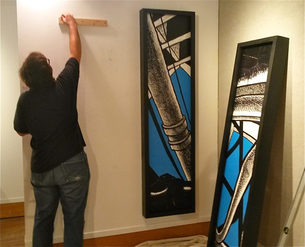 Thompson at work on hanging large paintings by Michael Nagara.