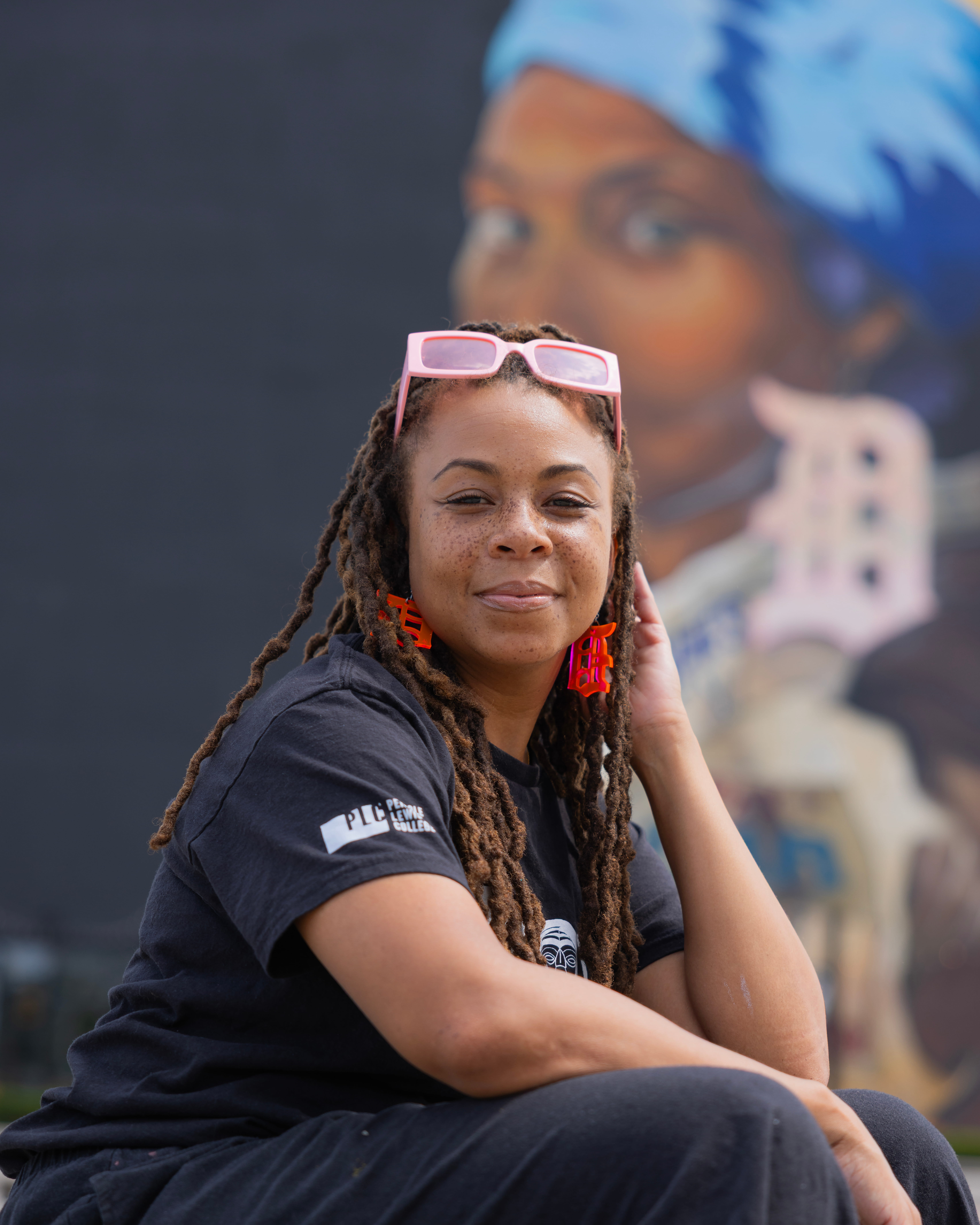 Portrait of a woman sitting in front of a mural.