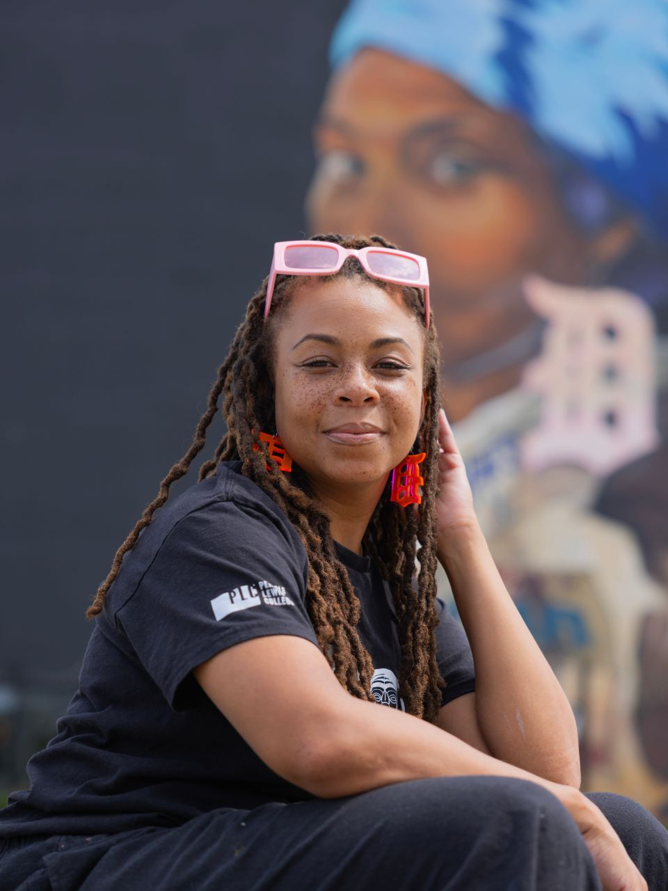 Portrait of a woman sitting in front of a mural.