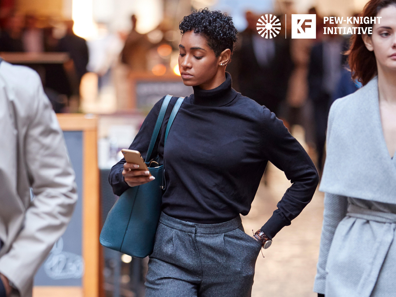 Young black businesswoman walking in the street using smartphone, selective focus